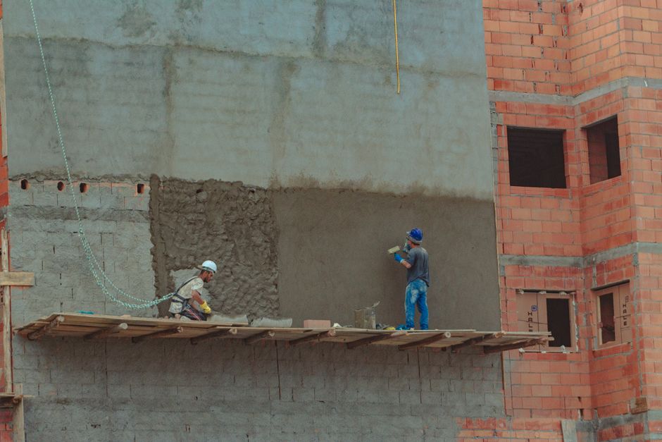 Vanjski prizor industrijske gradnje s drvenom konstrukcijom na cigličnom zidu i graditeljima u zaštitnim kacigama